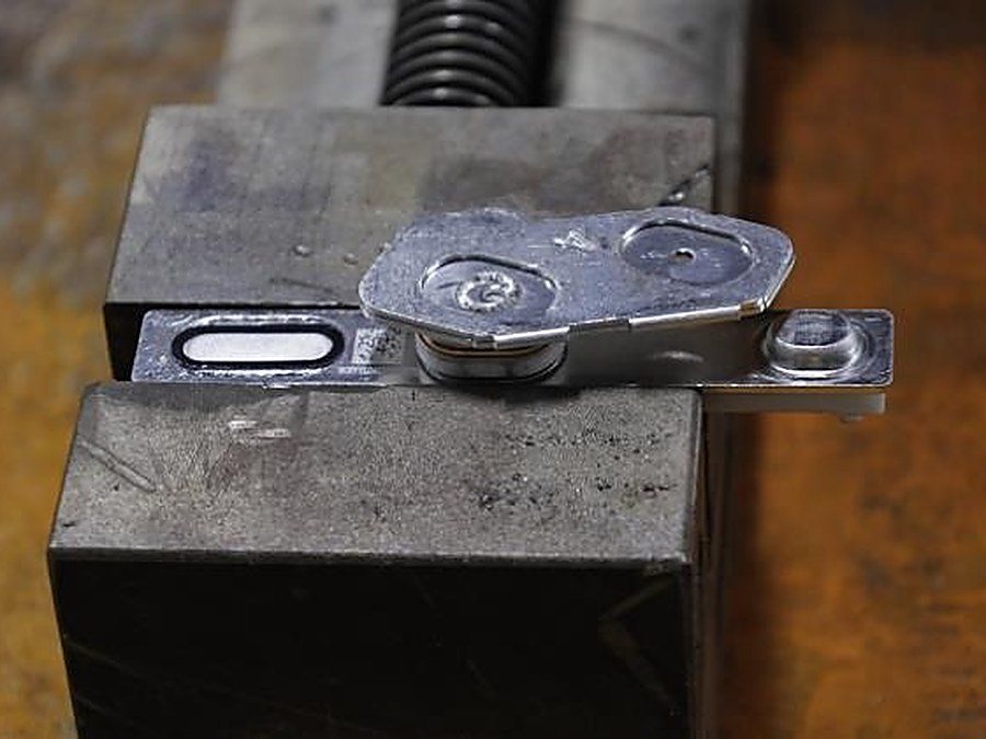 Laser welding torch running a seam on a stainless steel bracket
